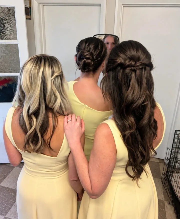 Three bridesmaids from behind, with softly waved half-up styles and a low brunette updo.