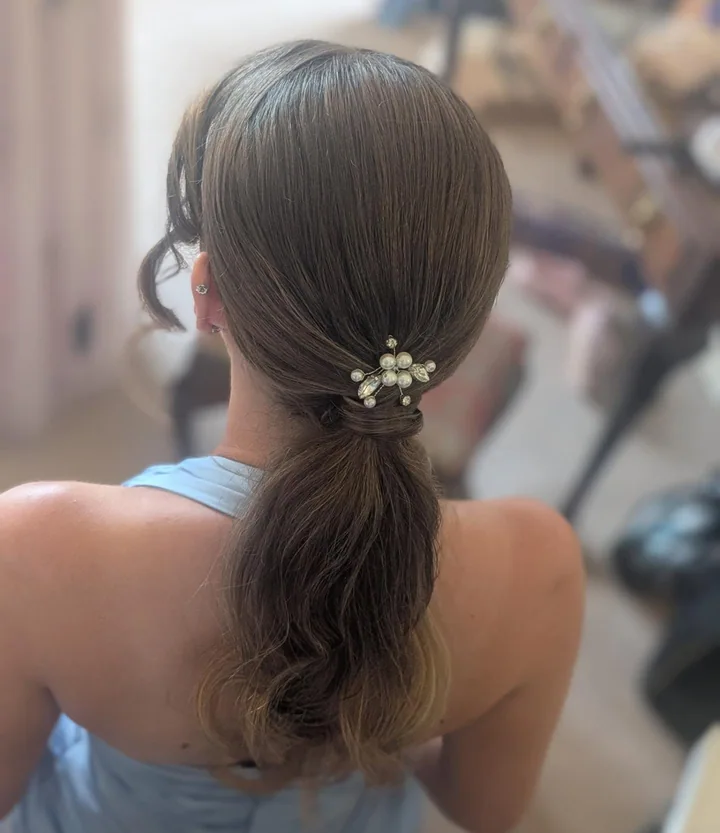 A sleek brunette ponytail with a decorative finish, created by Becky